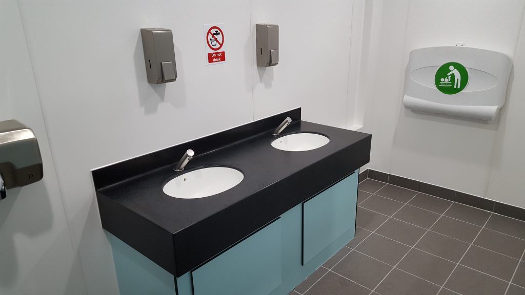 Two sinks and a wall mounted baby changing station at Corfe Castle.