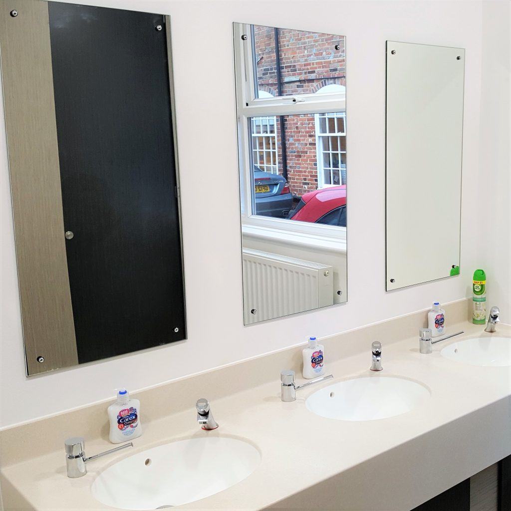 Three sinks and mirrors in Wessex Group bathrooms.