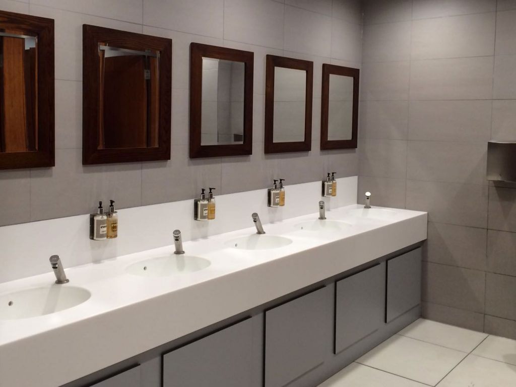 Four sinks and mirrors inside a ladies bathroom.
