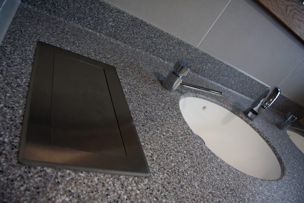 A sink, tap, soap dispenser with a marble surface.