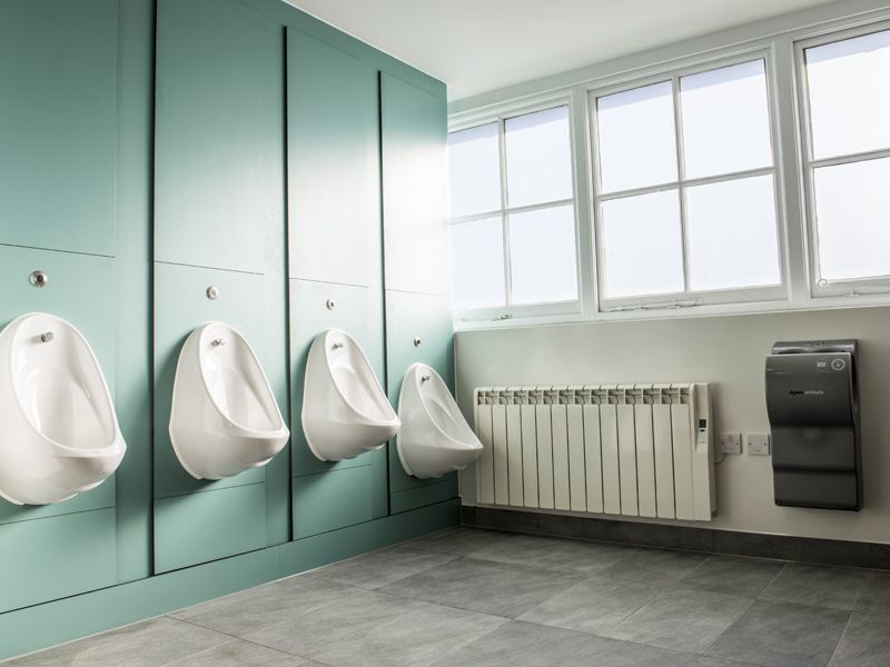 Four urinals and a hand dryer inside Washroom inside Clivedon House.