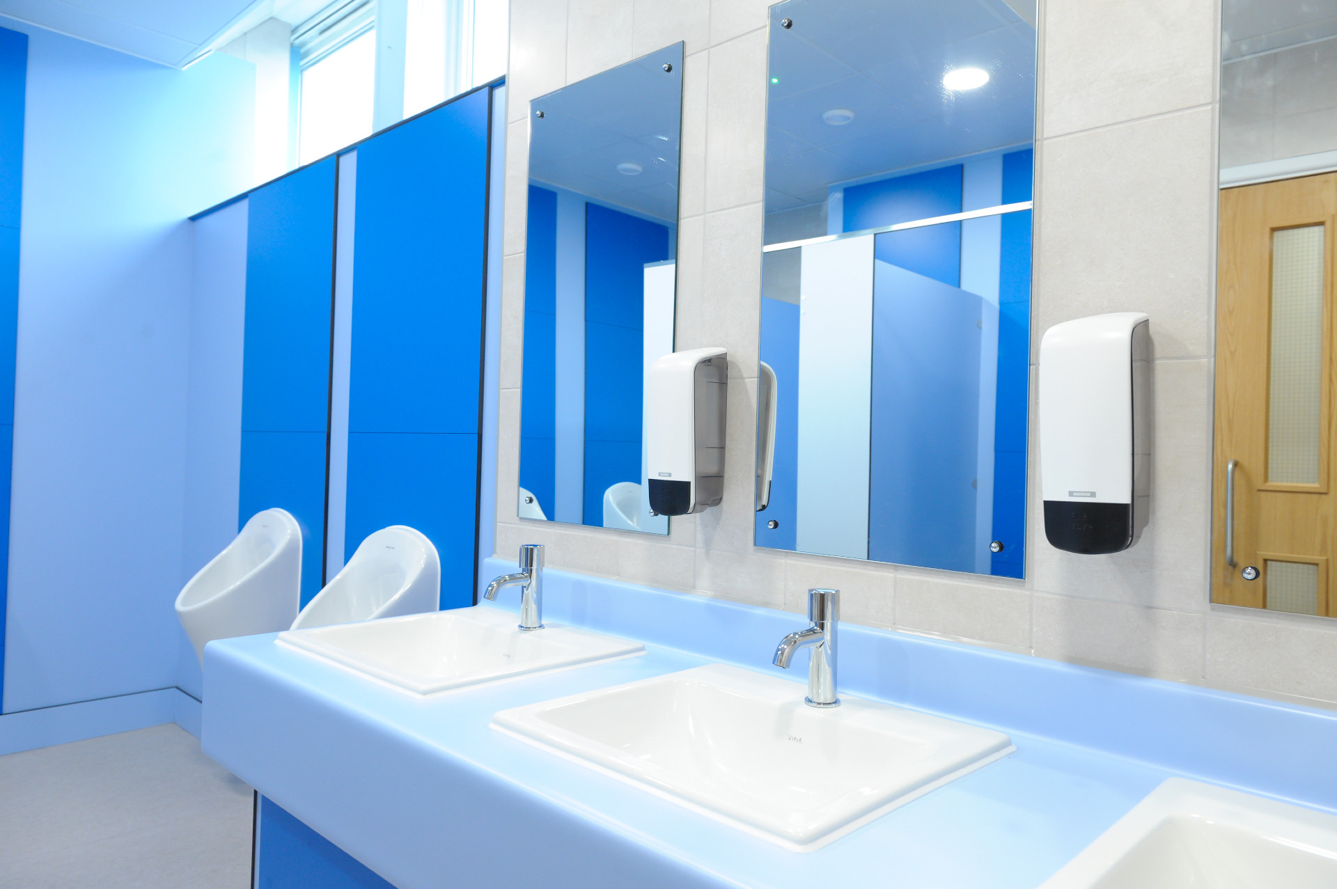 Urinals and sinks in a blue washroom.
