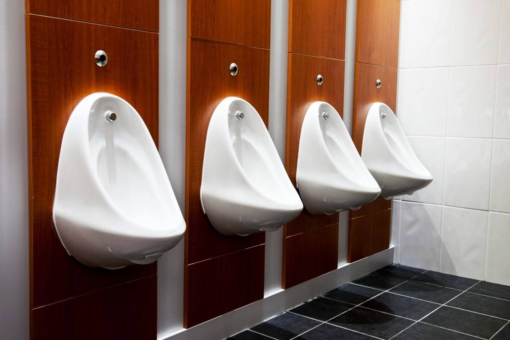 Four urinals next to each other on a wall.